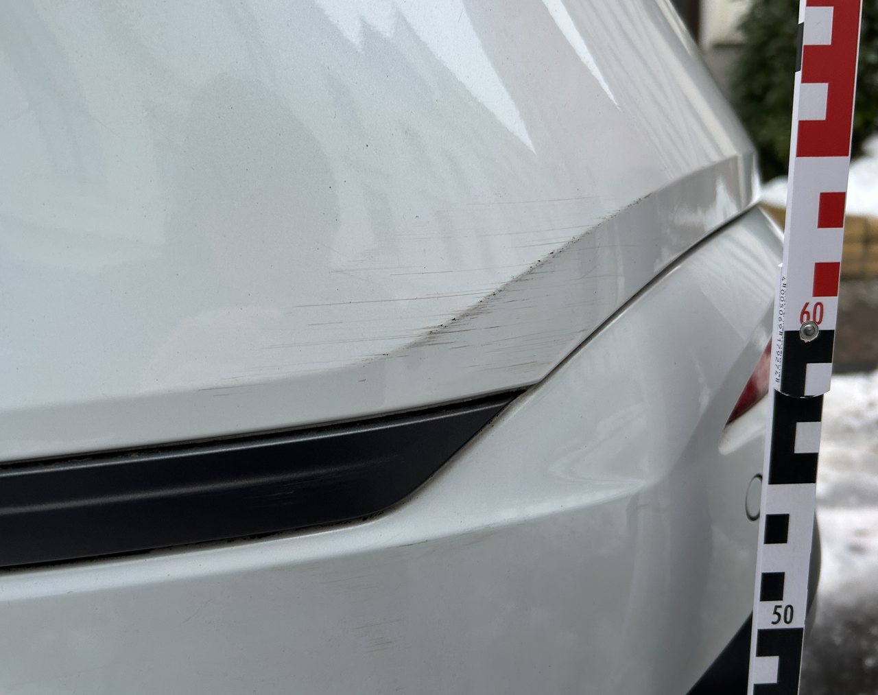Eindrückung mit Lackabtrag an der hinteren Seitenwand eines weißen Seat Tarraco, mit Messlatte dokumentiert, Schadenhöhe 4.737,26 €
