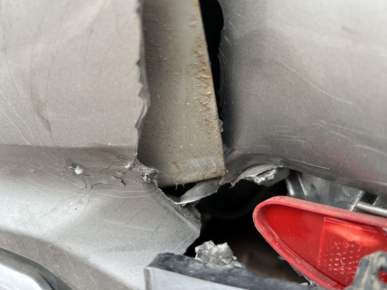 Aufgerissene hintere Seitenwand eines Unfallfahrzeugs, dahinter liegt der Träger frei